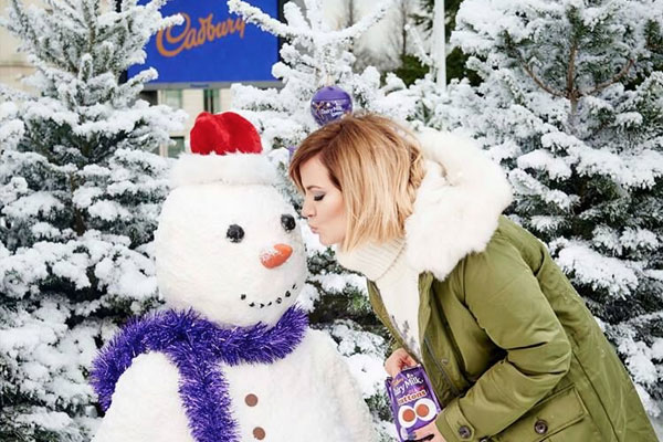 Lady kisses an artificial snow man in Cadbury pop up snow world