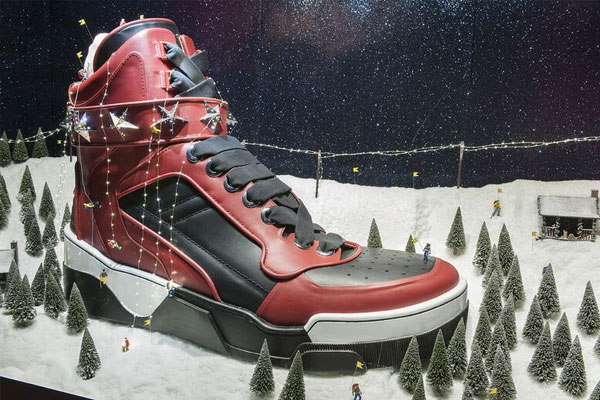 Christmas window display of  a giant shoe surrounded by miniature trees on a blanket of artificial snow